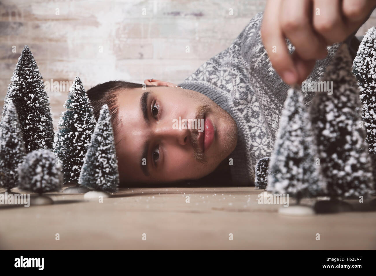 Junger Mann auf dem Boden liegend mit Christbaumkugeln Stockfoto