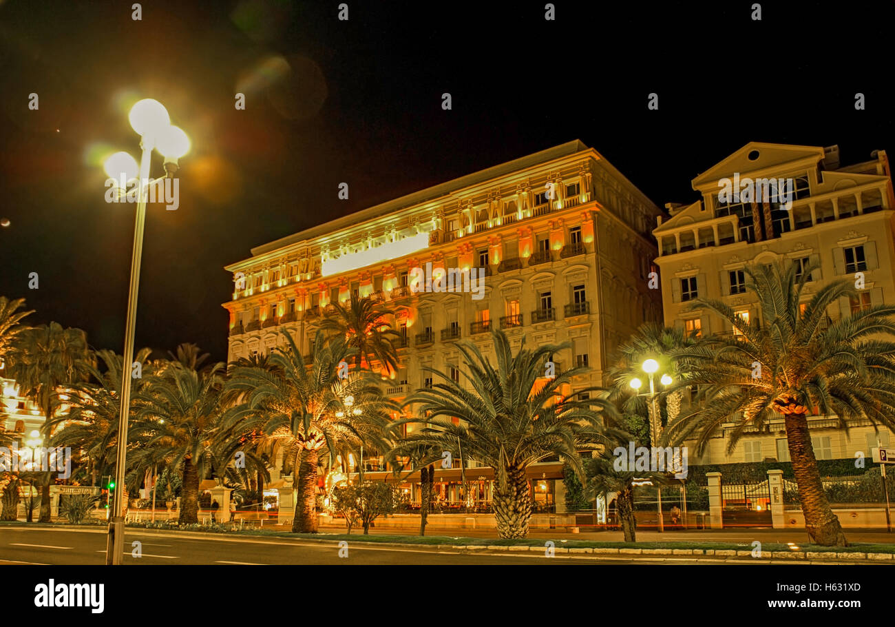 Der abendliche Spaziergang entlang der Promenade des Anglais mit Blick auf das malerische beleuchtete Gebäude des Hotel West-End, Nizza, Frankreich Stockfoto