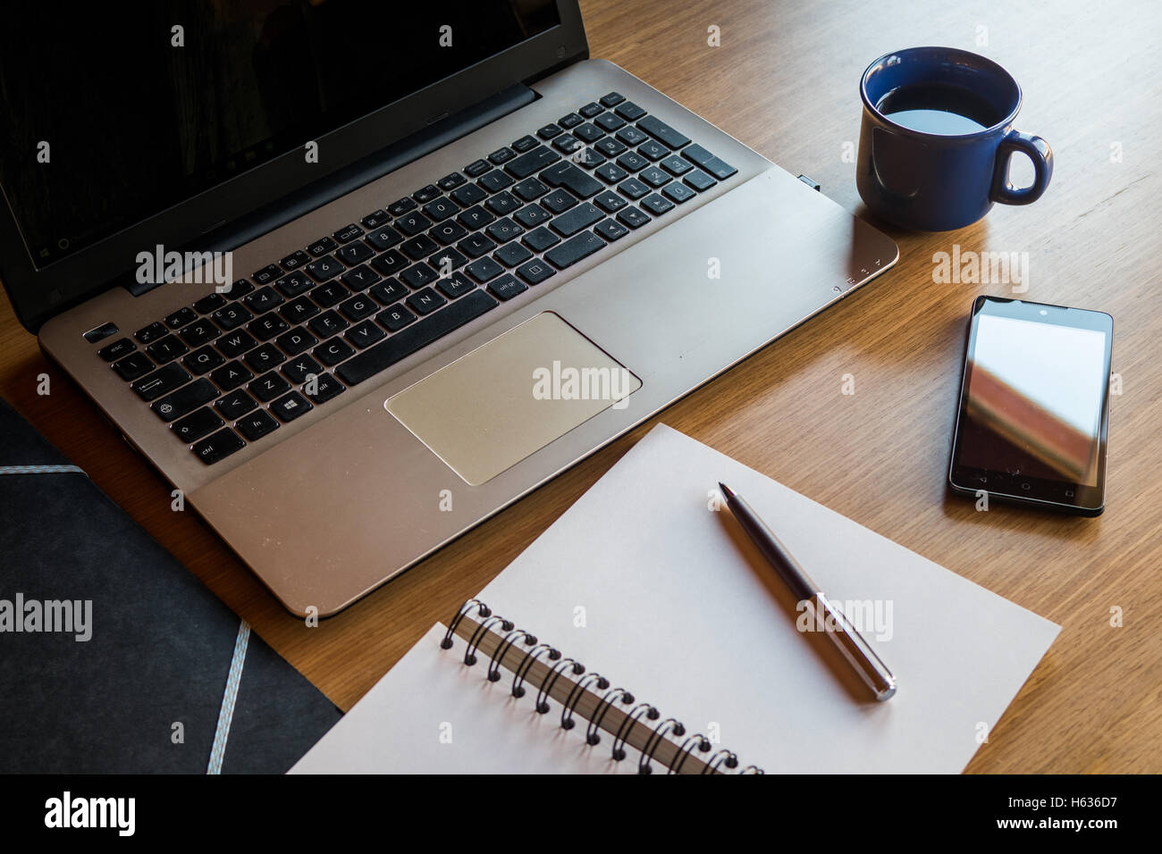 Schreibtisch mit Laptop, Smartphone, Notebook, Ordner und Kaffeetasse Stockfoto