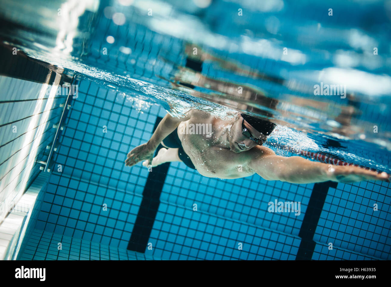Unterwasser Aufnahme des männlichen Profisportler Schwimmen im Pool. Junger Mann den vorderen Crawl in einem Pool schwimmen. Stockfoto