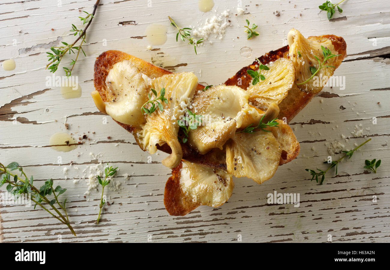 Gelbe Austernpilze in Butter gebraten, serviert mit Scambled Ei auf Sauerteig Toast mit wilde Rauke Stockfoto