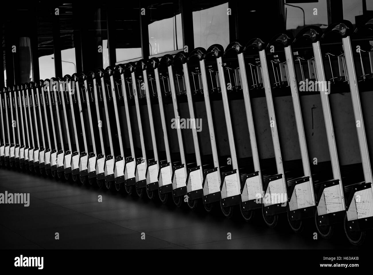 Gepäckwagen am Flughafen. Abstrakte Reihe von Gepäckwagen am Flughafen Stockfoto