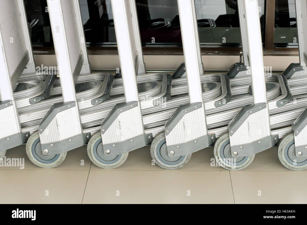 Gepäckwagen am Flughafen. Abstrakte Reihe von Gepäckwagen am Flughafen Stockfoto