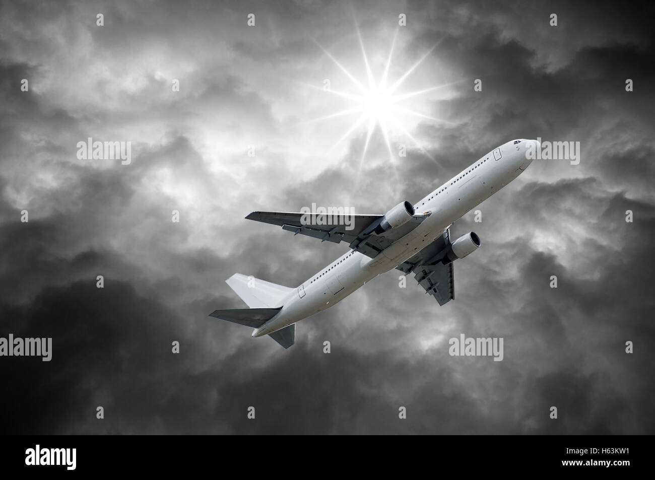 Flugzeug unter Sonne, die von dunklen Wolken des stürmischen Himmel leuchtet Stockfoto