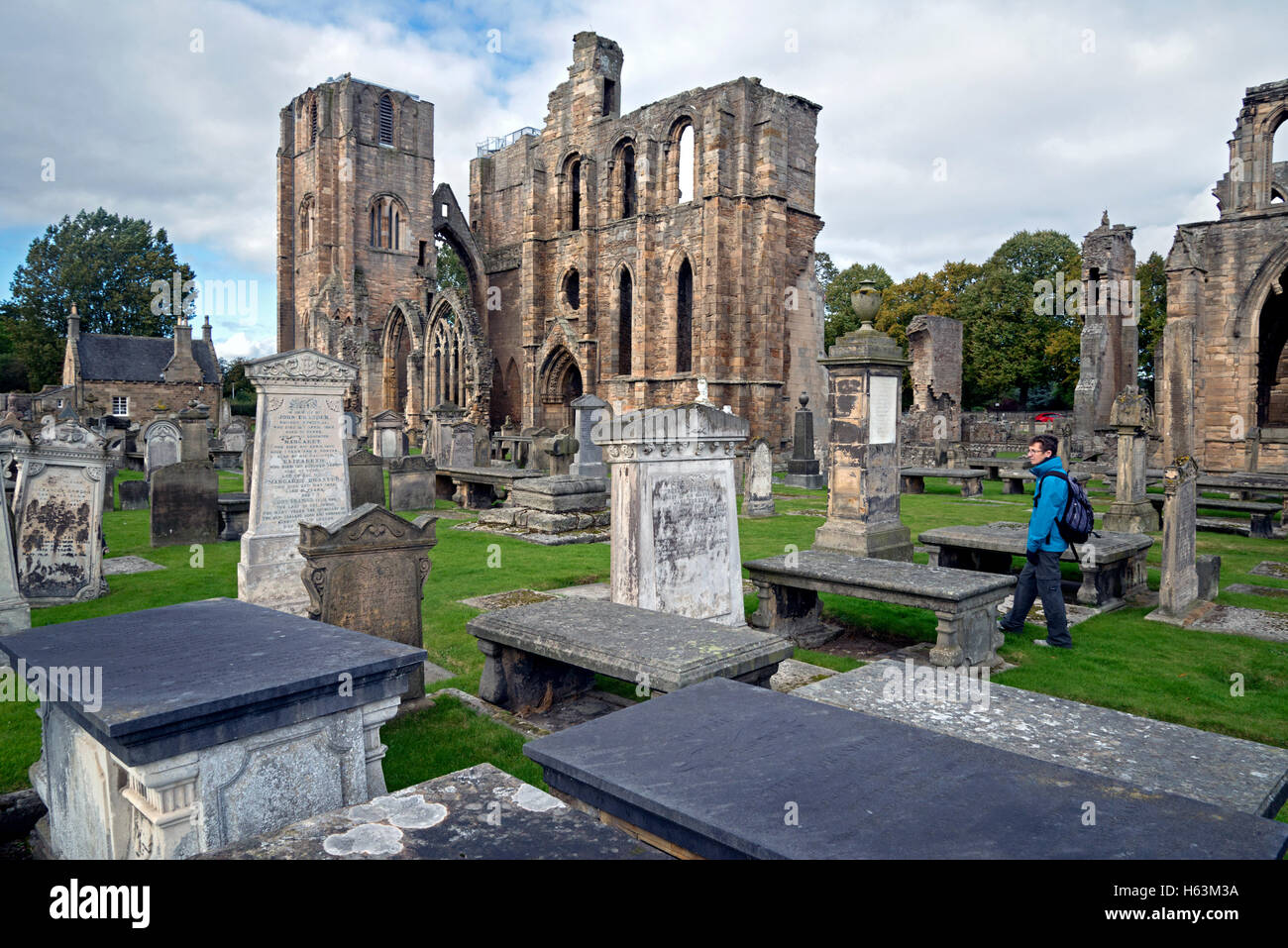 Ein Besucher geht durch den Friedhof von Elgin Cathedral in Elgin, Morayshire, Schottland, Vereinigtes Königreich. Stockfoto