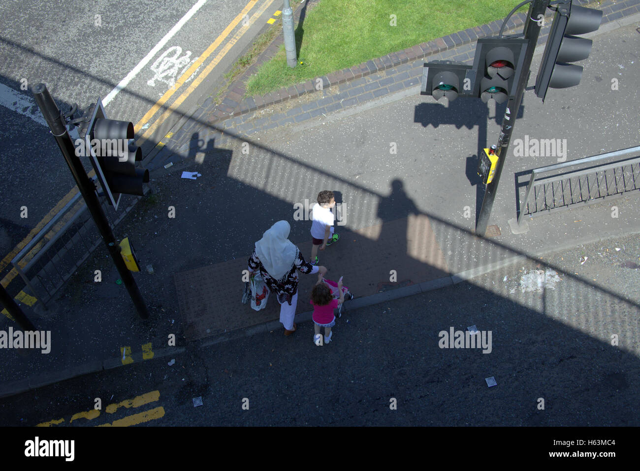 Einwanderer-Familie auf Bürgersteig in der Nähe von Ampeln, Glasgow, Schottland Stockfoto
