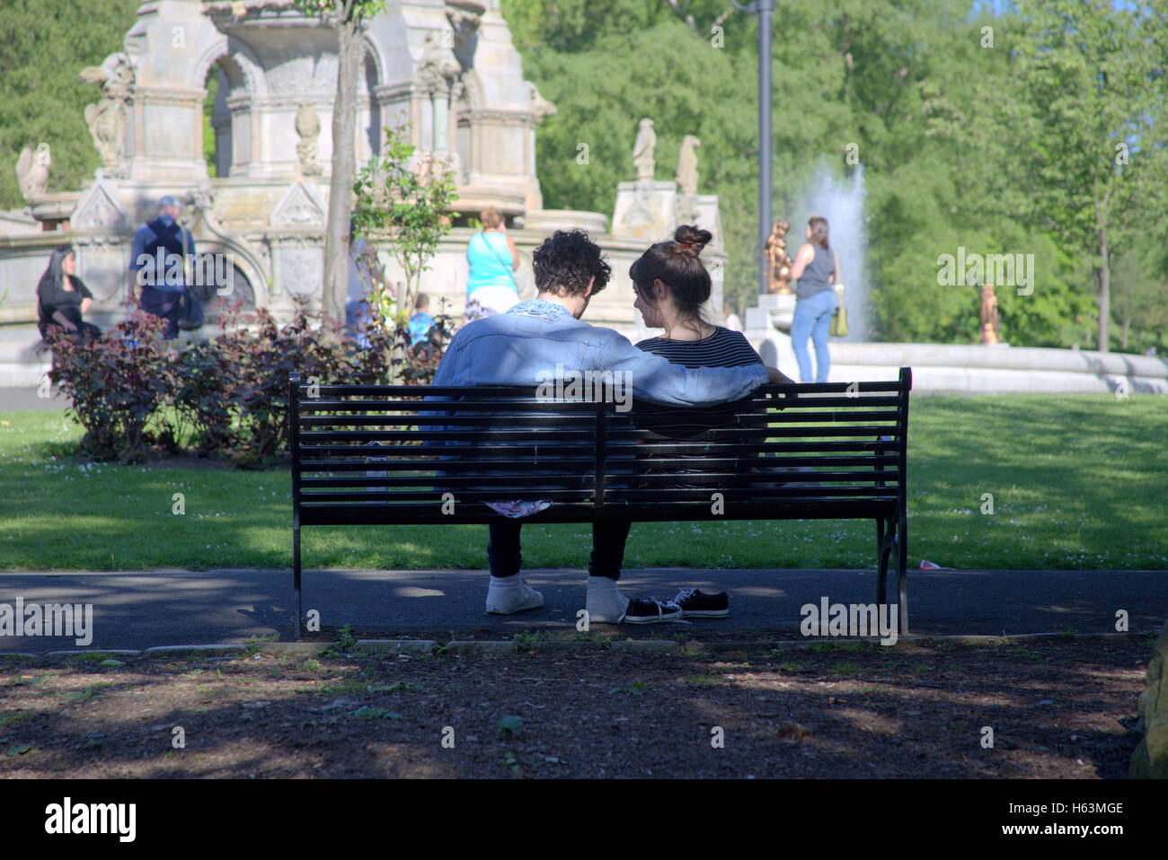 Junges Paar auf Bank Glasgow Kelvingrove Park enthält die Universität und das Museum in der Parkanlage Stockfoto