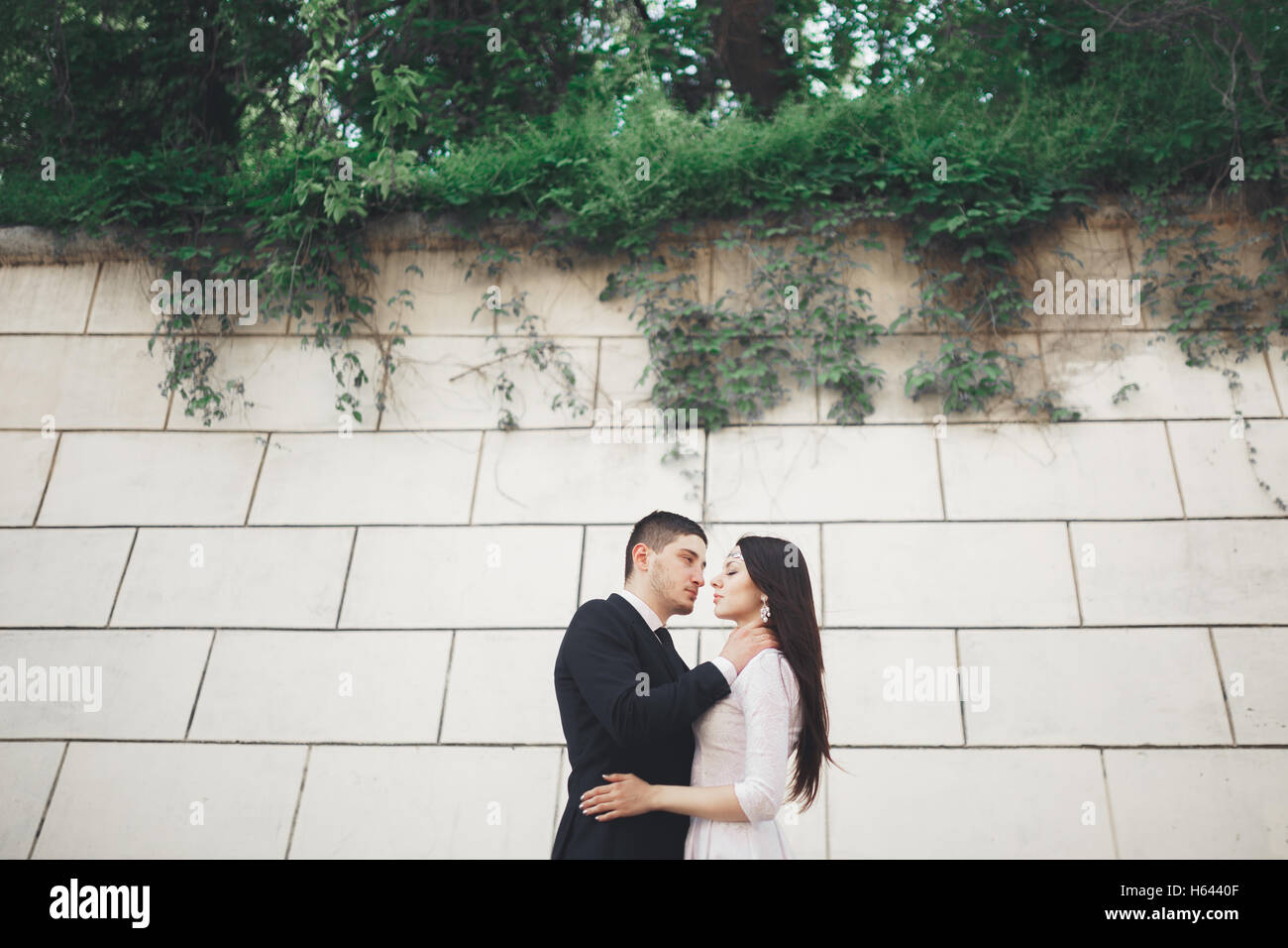 Wunderschöne Luxus Brautpaar posiert in der Nähe von großen Mauer Stockfoto