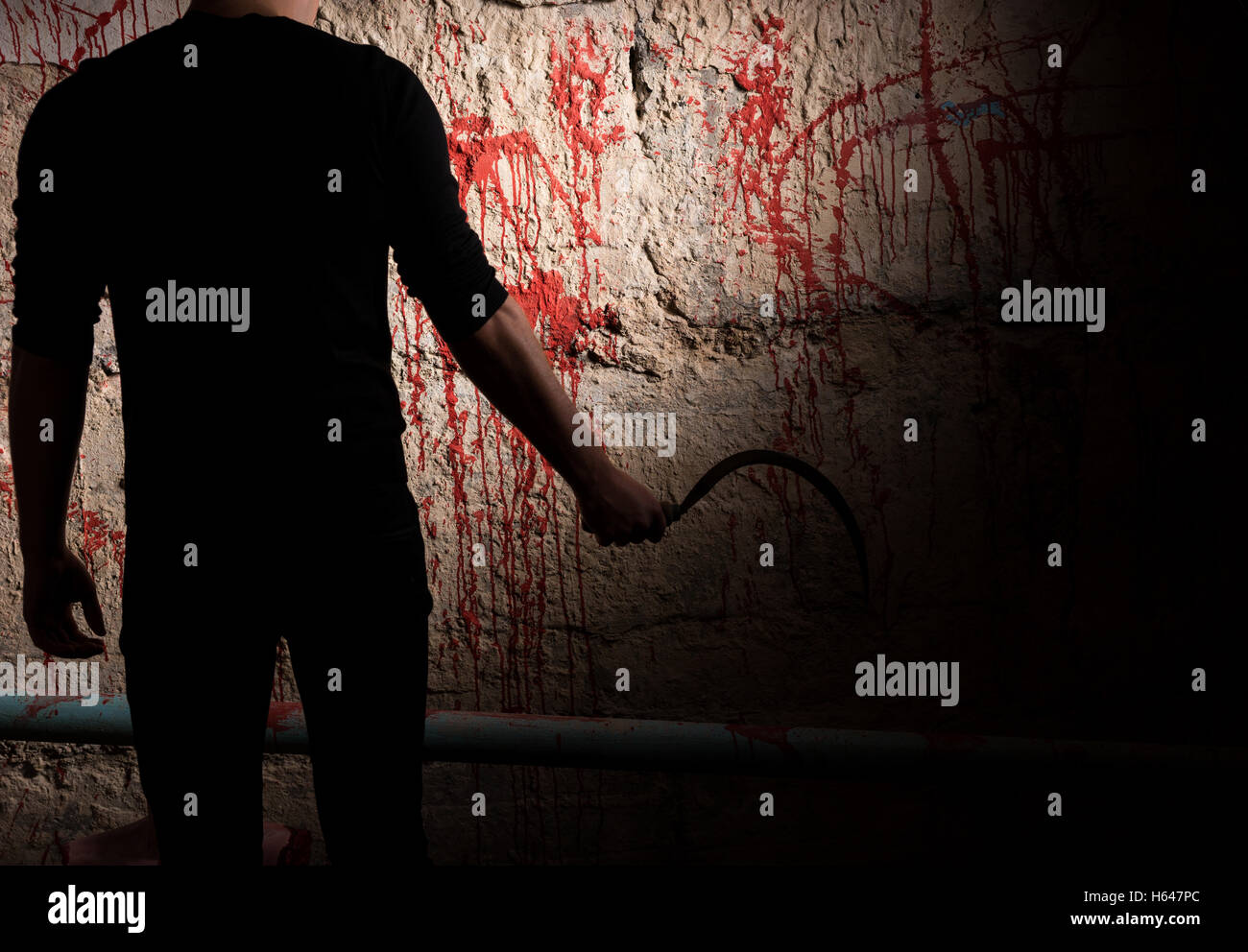 Schattenhafte männliche Figur, Klinge in der Nähe von Blut befleckt Wand zum Konzept über Morde und gruselige Halloween-Urlaub Stockfoto