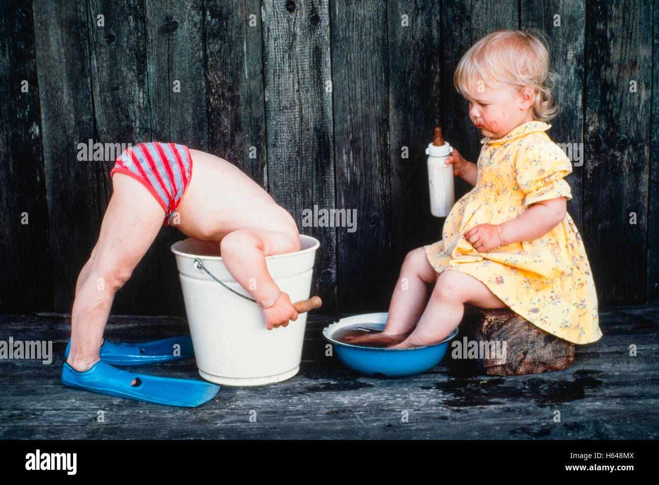 Drei Jahre alten Mädchen badet ihre Füße, junge steckt Kopf in Eimer,  Österreich Stockfotografie - Alamy