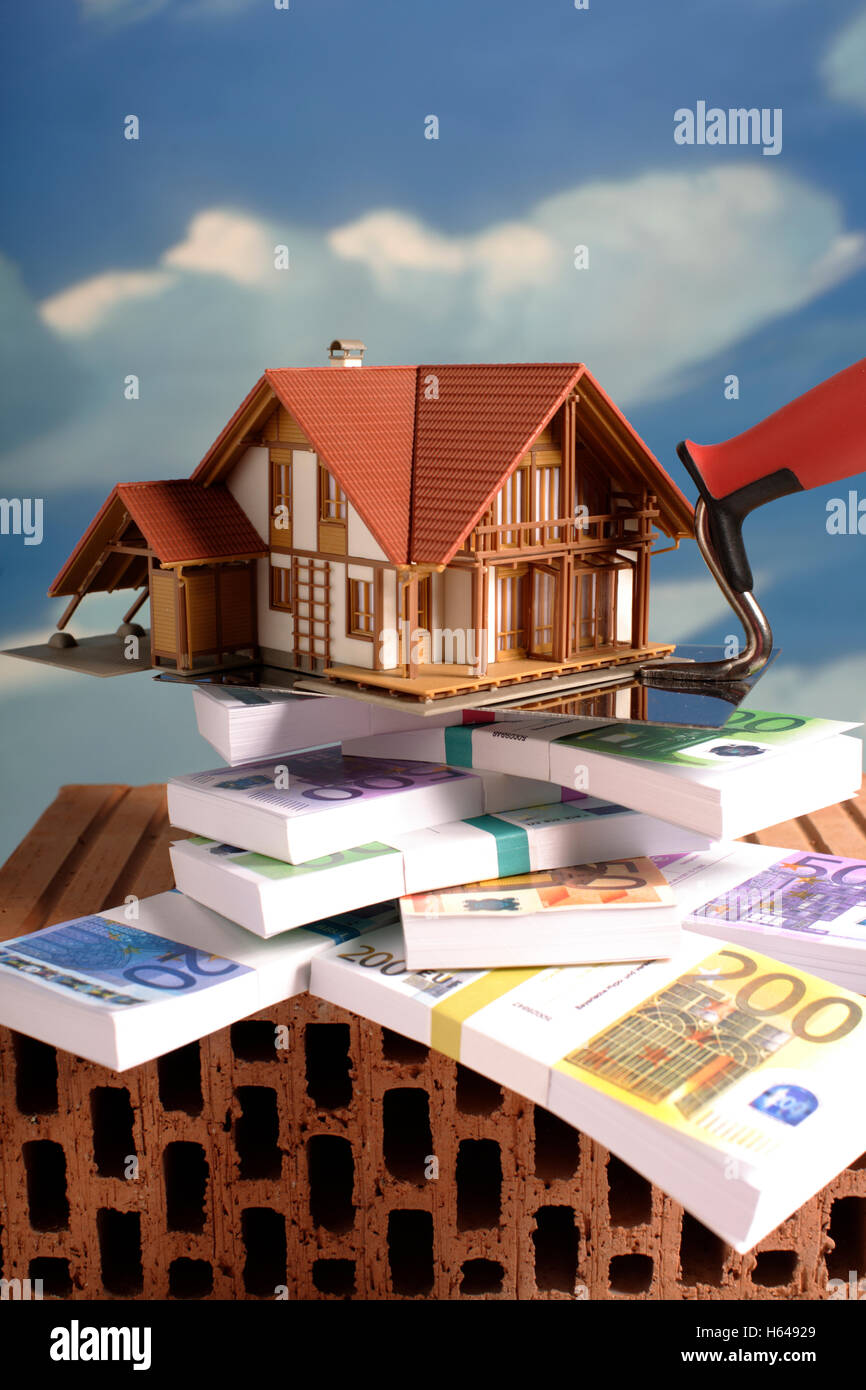 Banknoten, Modell eines Hauses, Kelle, Ziegel, symbolisches Bild für Bank Hypothek Bausparen Stockfoto