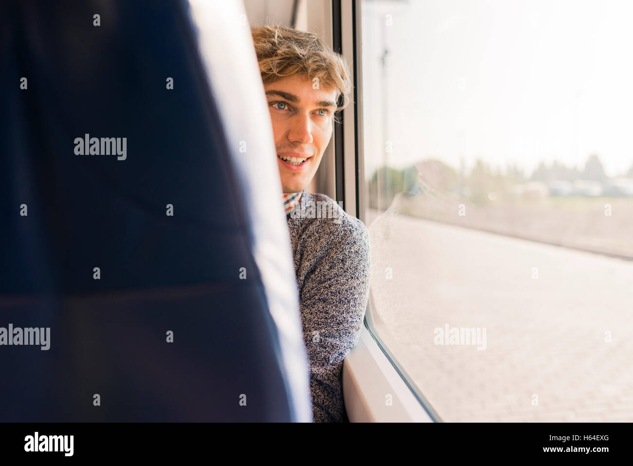 Junger Mann sitzt in einem Zug Blick durch Fenster Stockfoto