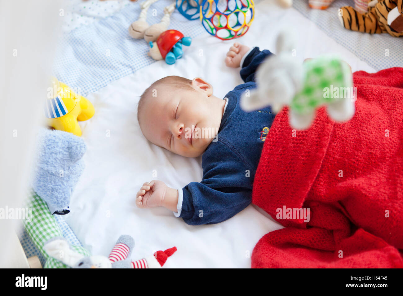Baby schläft im Laufstall mit Spielzeug Stockfoto