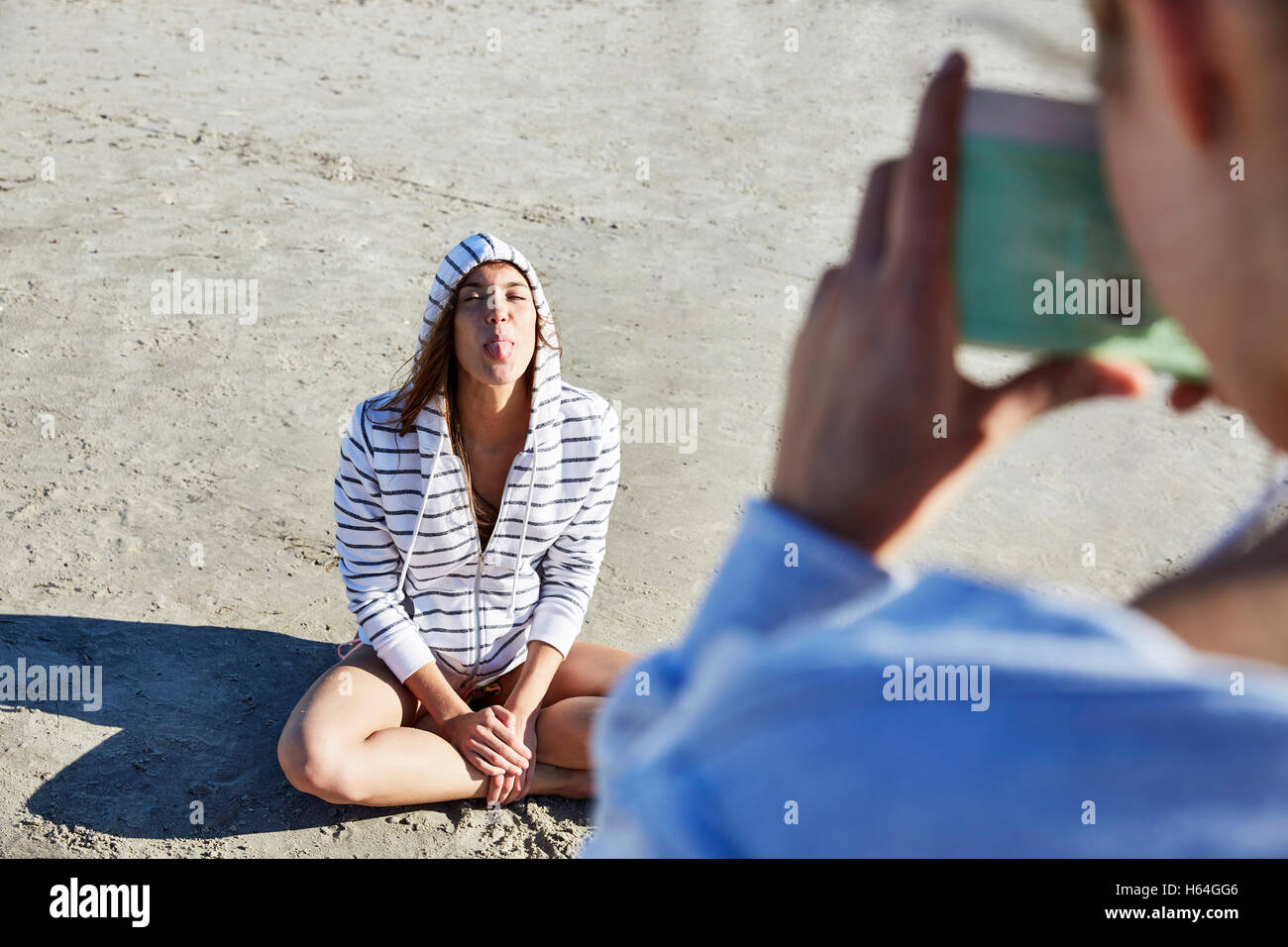 Frau unter Bild der Freund ihrer Zunge draußen am Strand Stockfoto