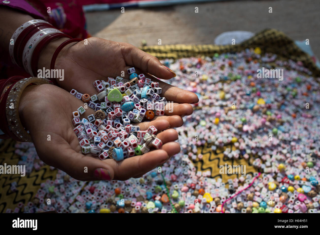 Eine Frau hält quadratische geformte Perlen mit englischen Alphabete in ihren Händen Stockfoto