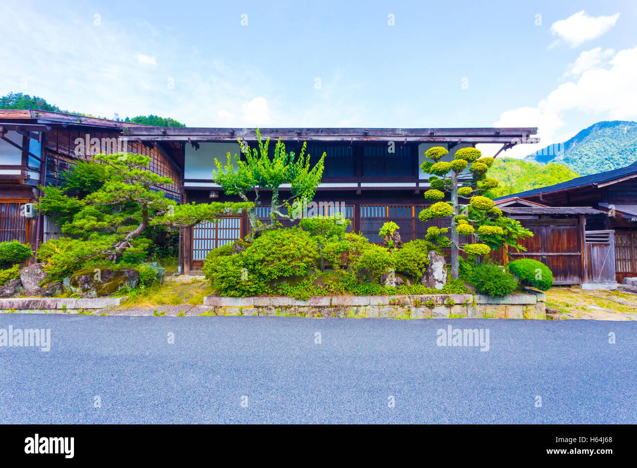 Vor einem traditionellen Holzhaus mit ordentlich gepflegten japanischen Garten entlang der Nakasendo in Tsumango, Japan Stockfoto