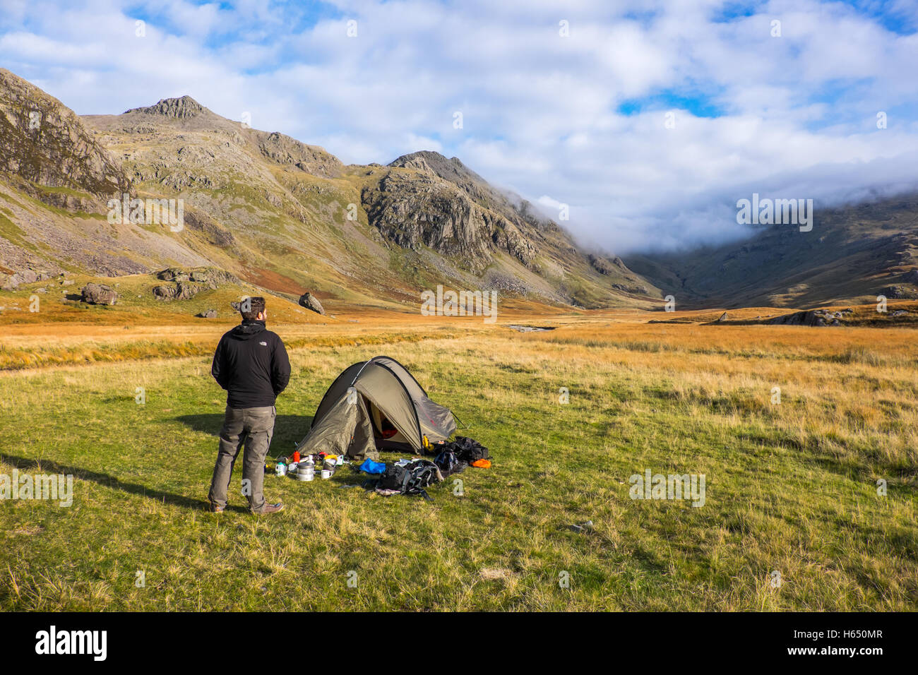 Wildes Campen in der oberen Esk Valley im Lake District, ein junger Mann steht durch seine Hütte Stockfoto