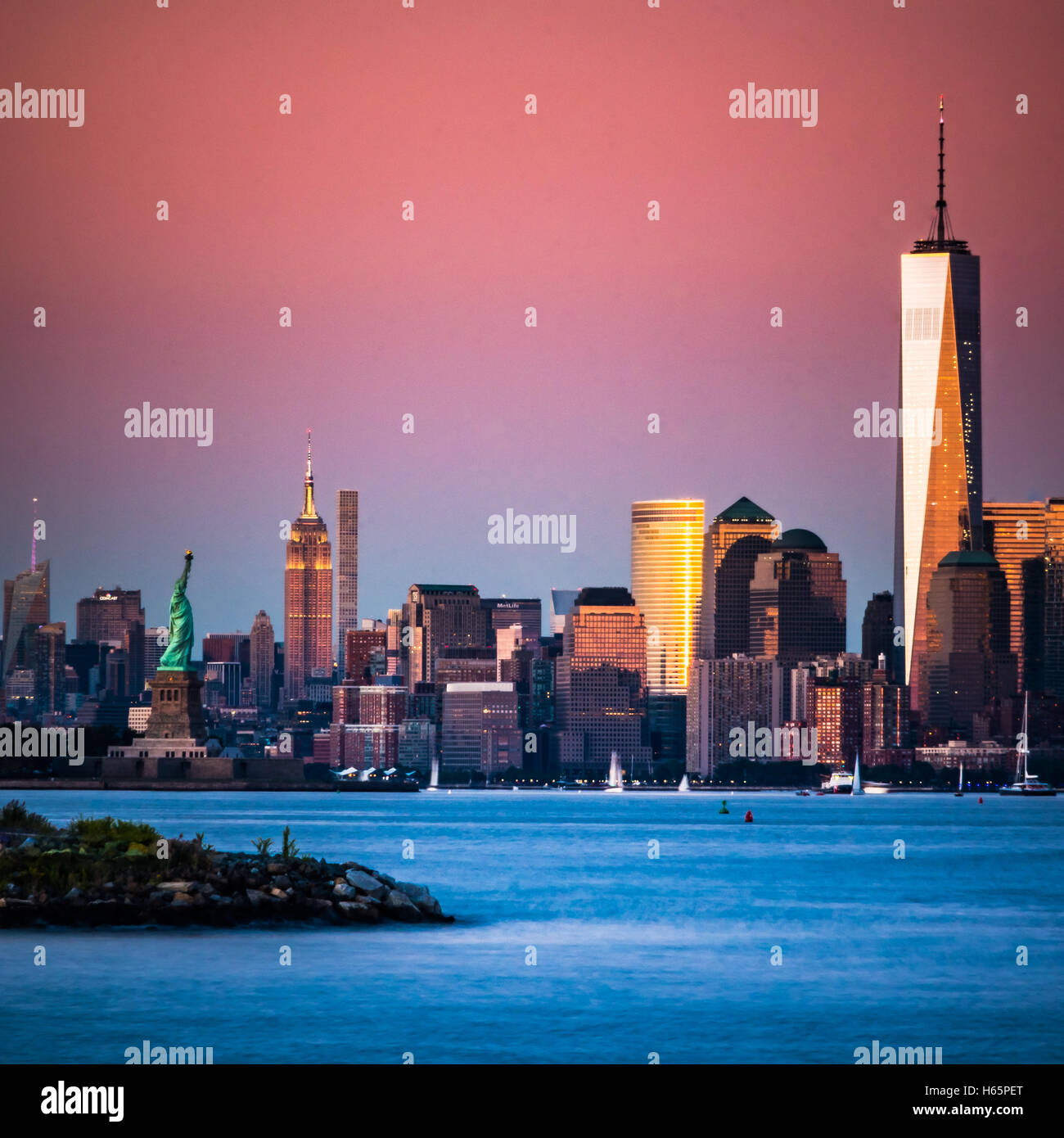 Lower Manhattan bei Sonnenuntergang. Der Freedom Tower, One World Trade Center, Empire State Building und die Freiheitsstatue zusammen Stockfoto
