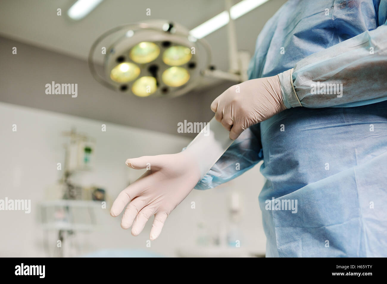 Chirurgen setzen auf sterile Gummihandschuhe zu komplizierten chirurgischen Eingriff auf die Hintergrund-Beleuchtung. Chirurgie Stockfoto