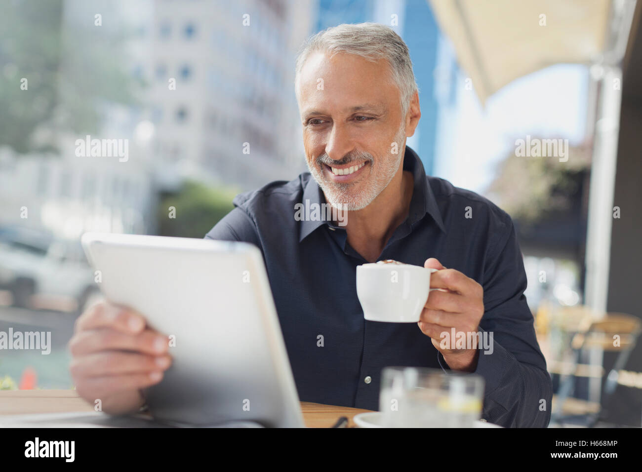 Lächelnd Geschäftsmann mit digital-Tablette Kaffeetrinken in städtischen Straßencafé Stockfoto
