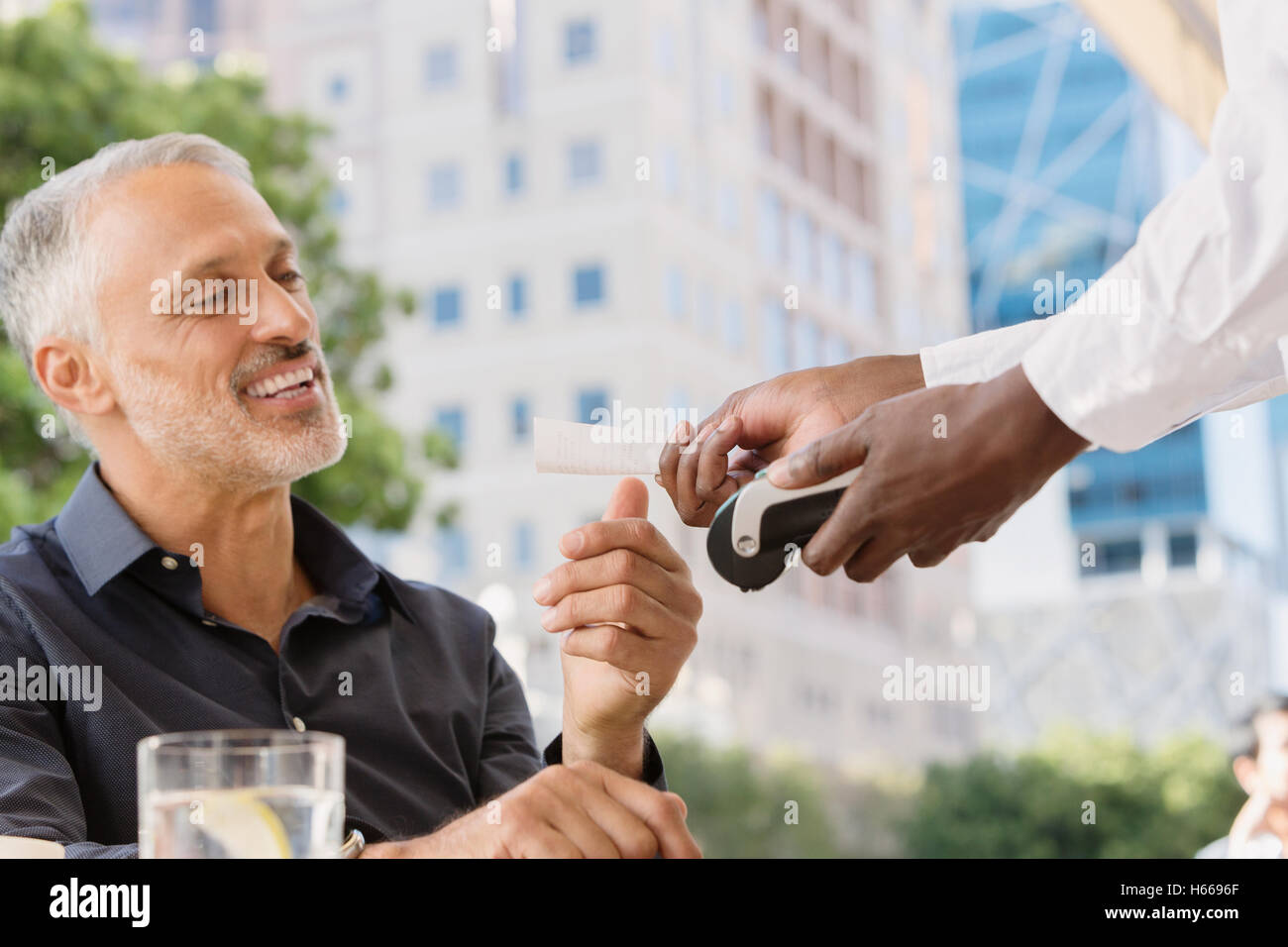 Kellner mit Kreditkartenleser geben Mann Erhalt in städtischen Straßencafé Stockfoto
