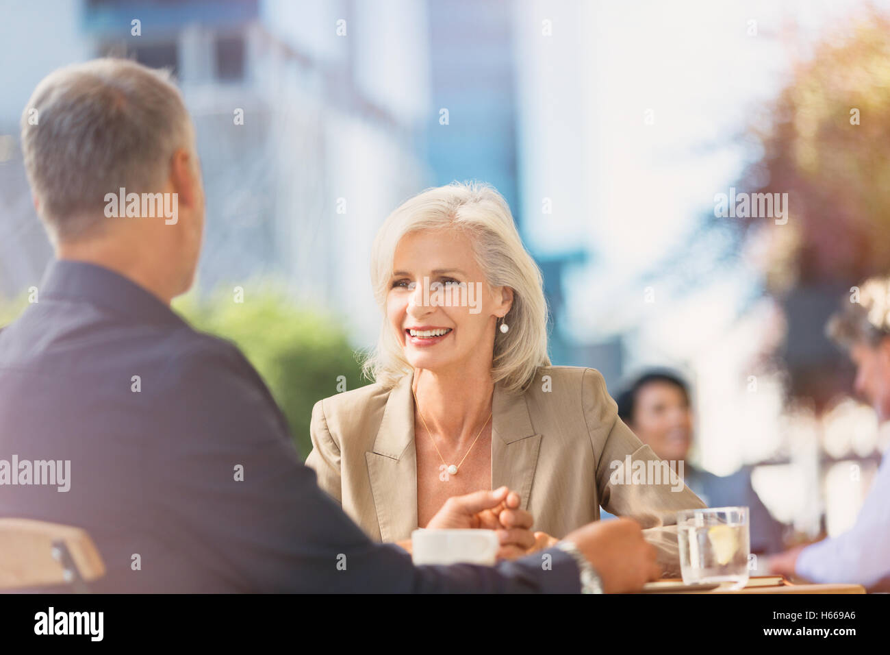 Lächelnde Geschäftsfrau, Geschäftsmann in sonnigen urban Straßencafé anhören Stockfoto