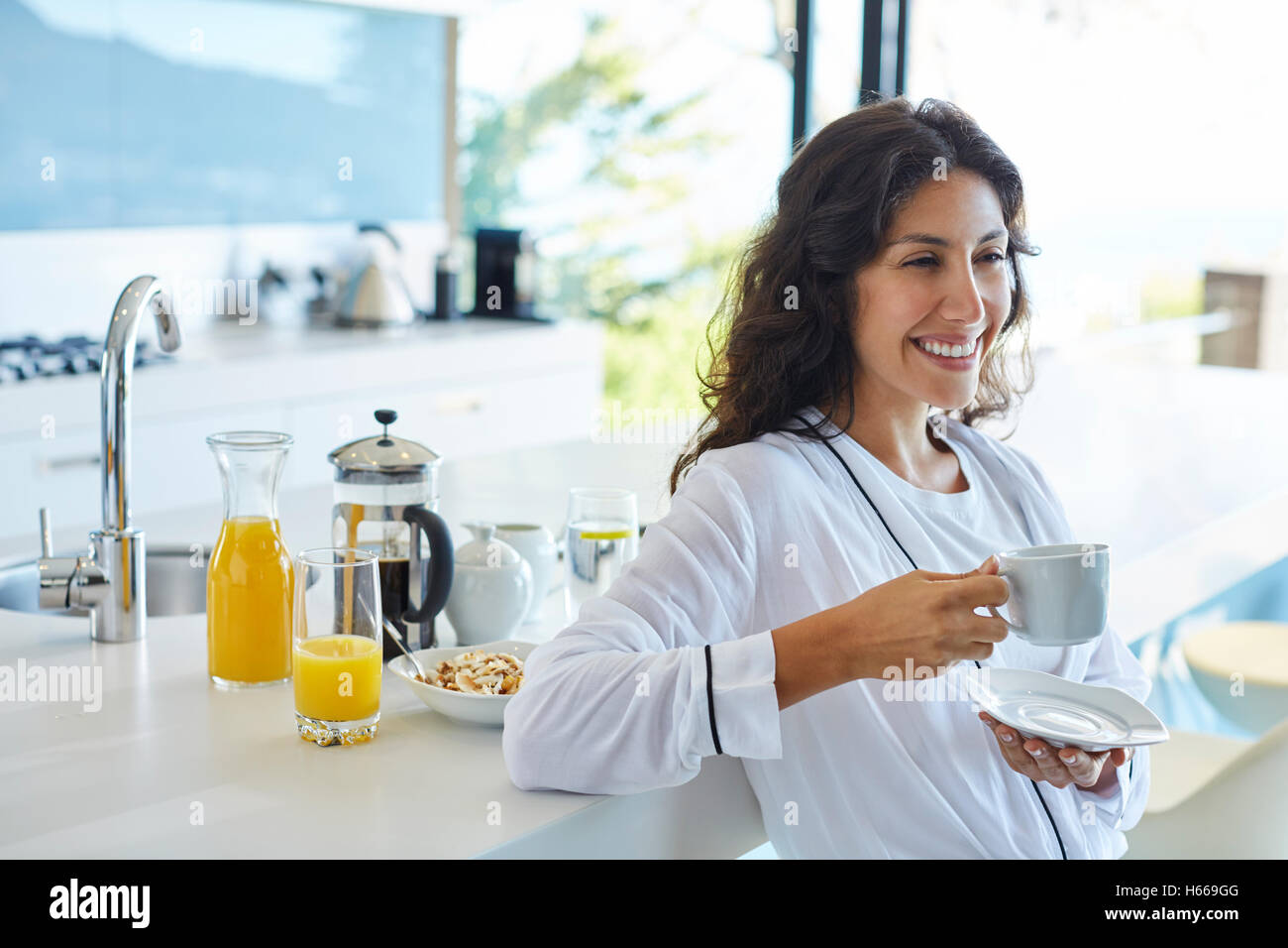 Lächelnde Frau in Bademantel Kaffeetrinken in Morgen Küche Stockfoto