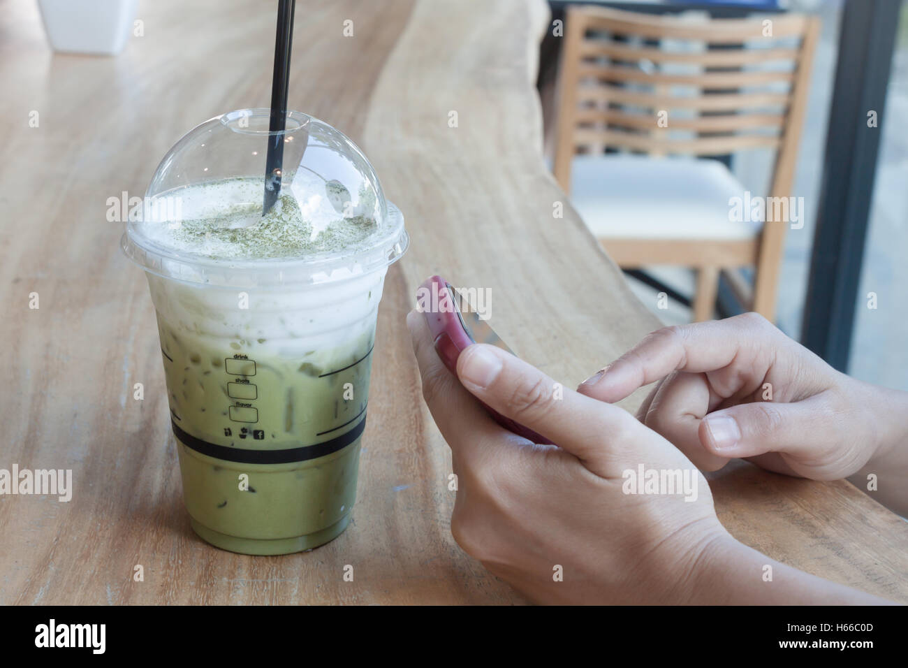 Frau Hand mit Telefon mit Hintergrund grün Eistee, Fotoarchiv Stockfoto