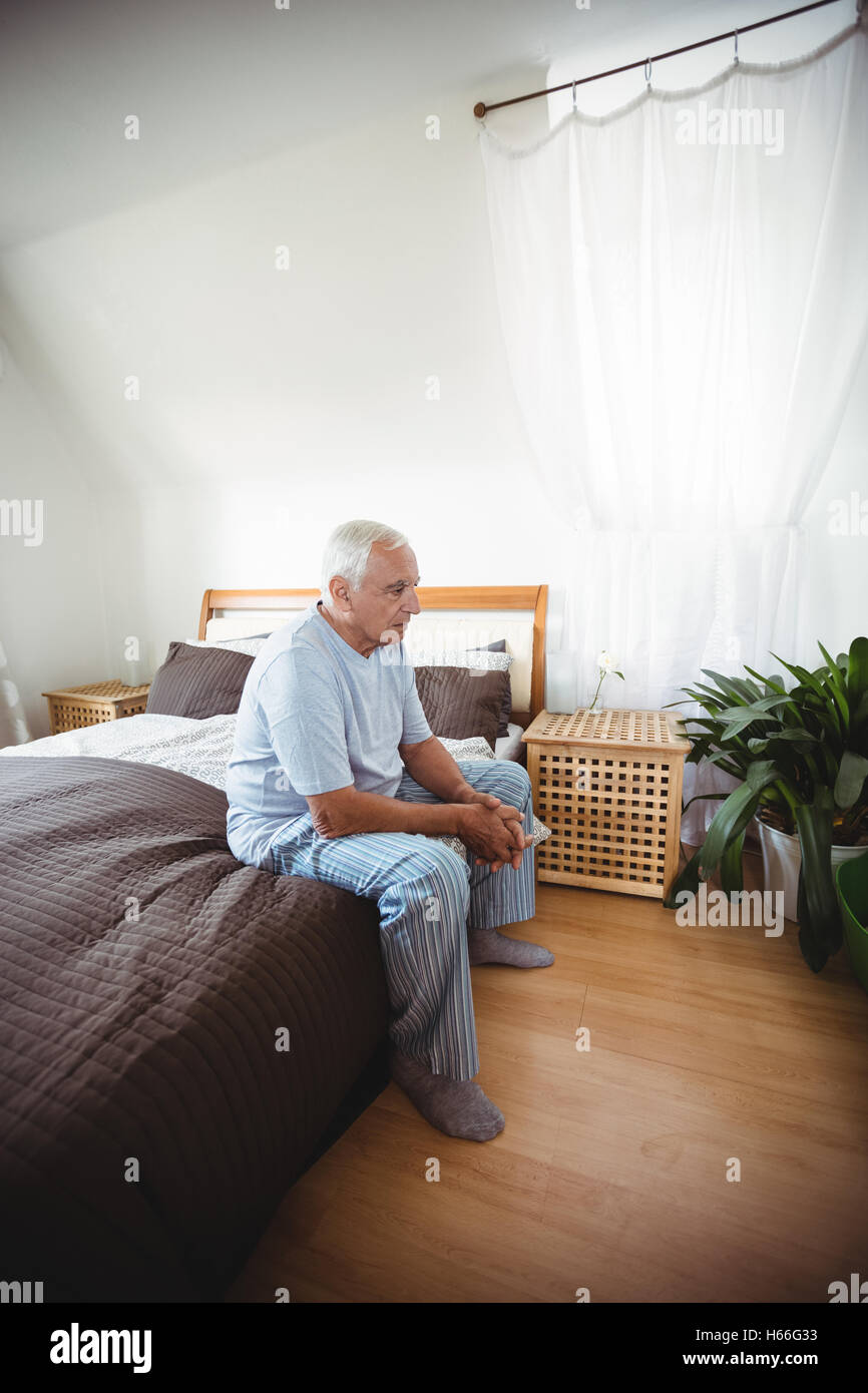 Nachdenklicher senior Mann sitzt auf Bett Stockfoto