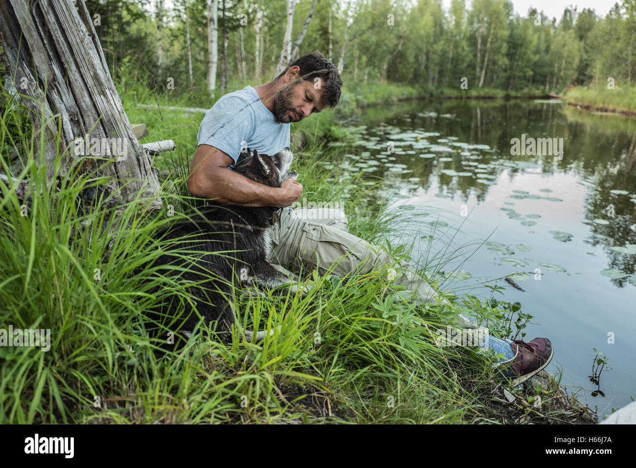 Man spielt mit dem Hund am Ufer des Sees Stockfoto