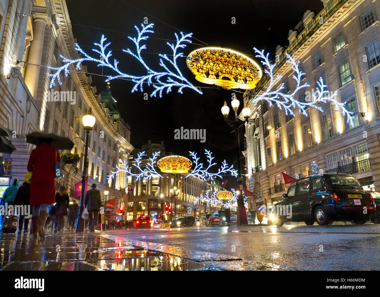 Belebten Szene Weihnachts-Shopper, Verkehr und Schirme in einem Regen fegte die Regent Street mit Weihnachtsbeleuchtung hinter London UK Stockfoto