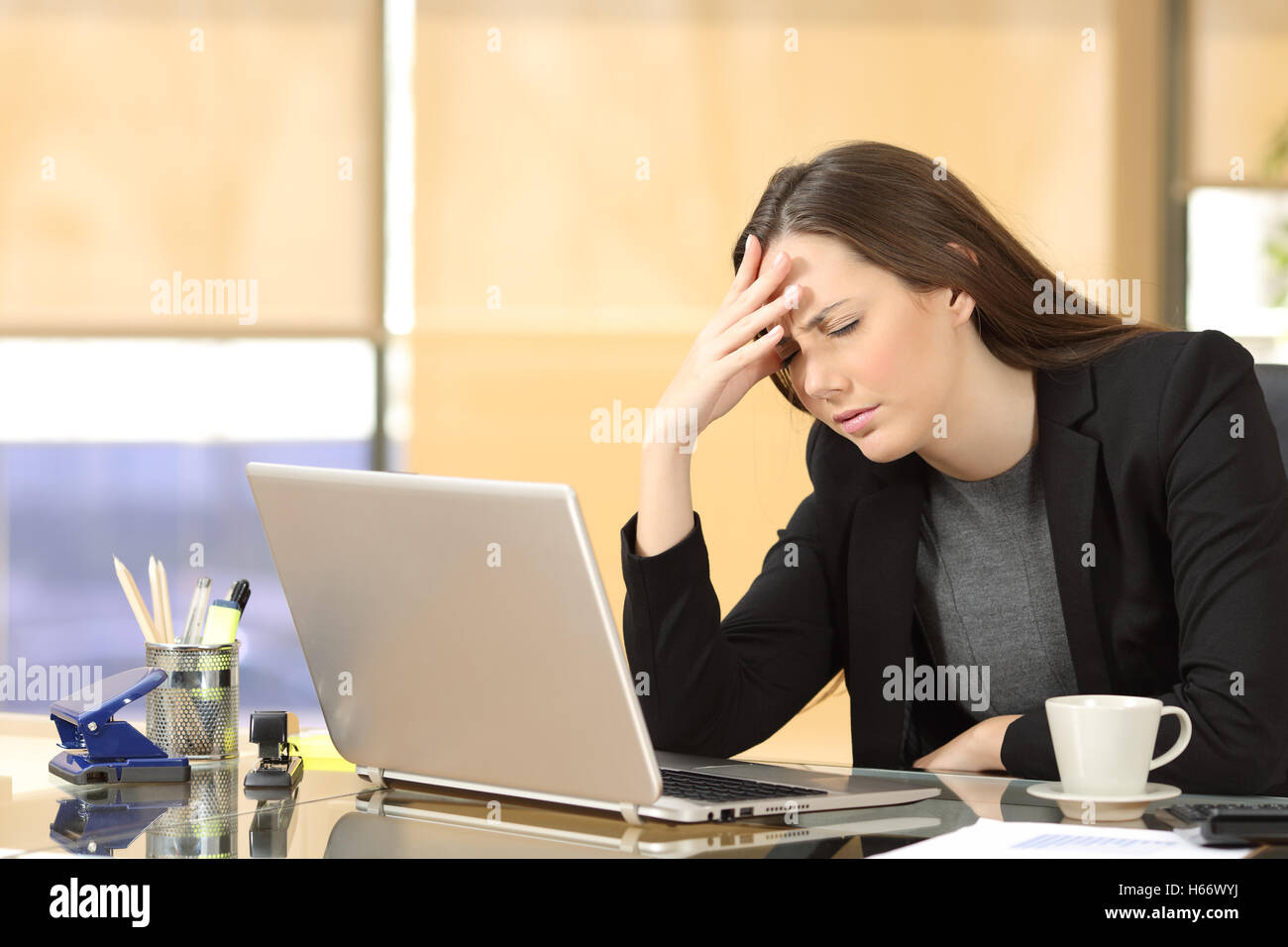 Geschäftsfrau Leiden Migräne bei Arbeit auf Linie mit einem Laptop in einem Desktop im Büro sitzen Stockfoto