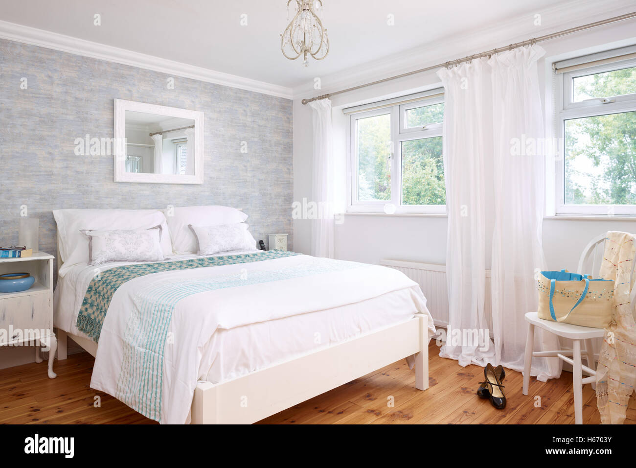 Ein Stil, leichte, frische Schlafzimmer in einem typischen UK nach Hause, zeigen einem gemachten Bett, Parkettboden & dual Aspekt windows Stockfoto