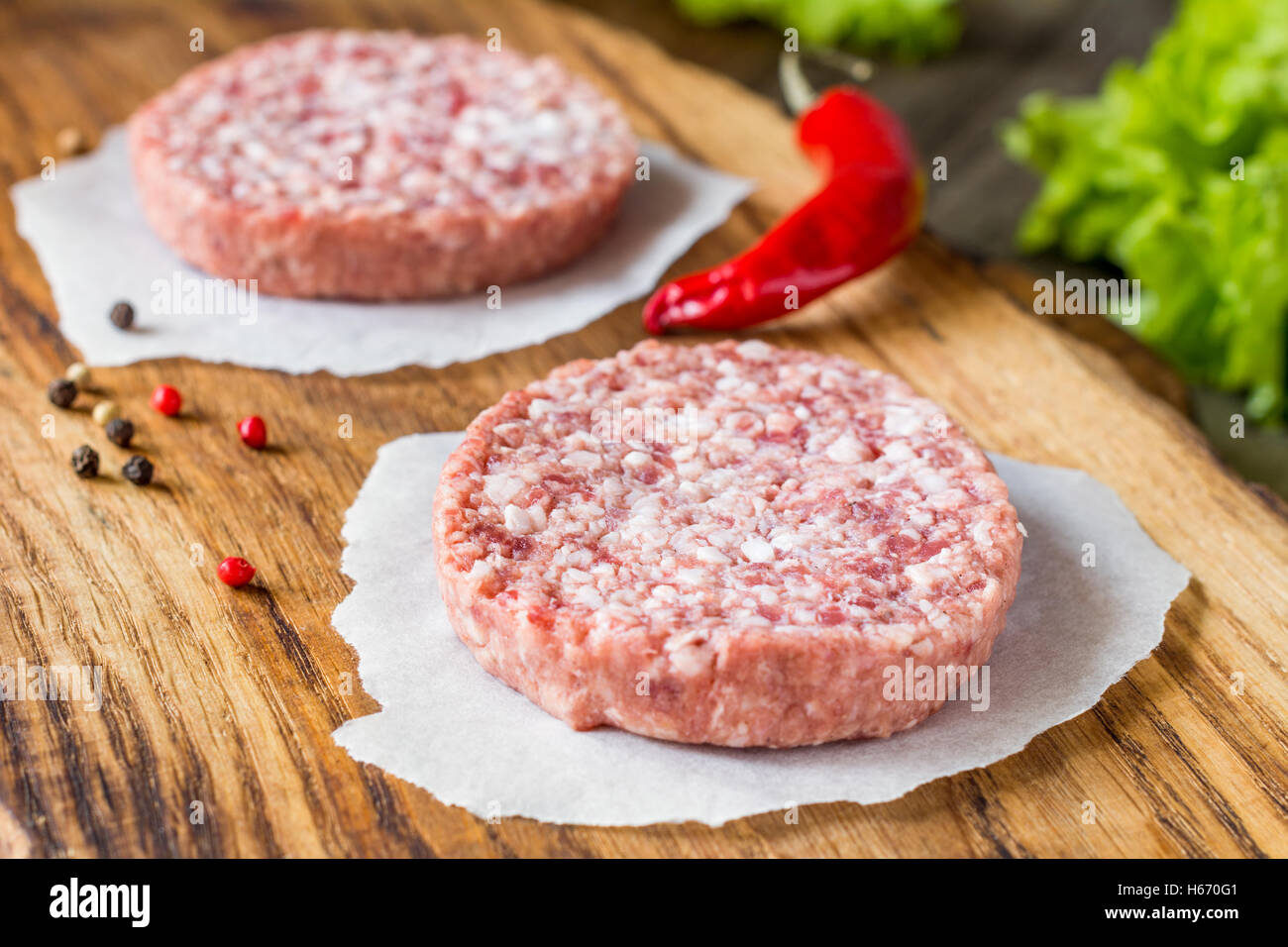 Rohe frische Burger Frikadellen auf Schneidbrett aus Holz. Nahaufnahme Stockfoto