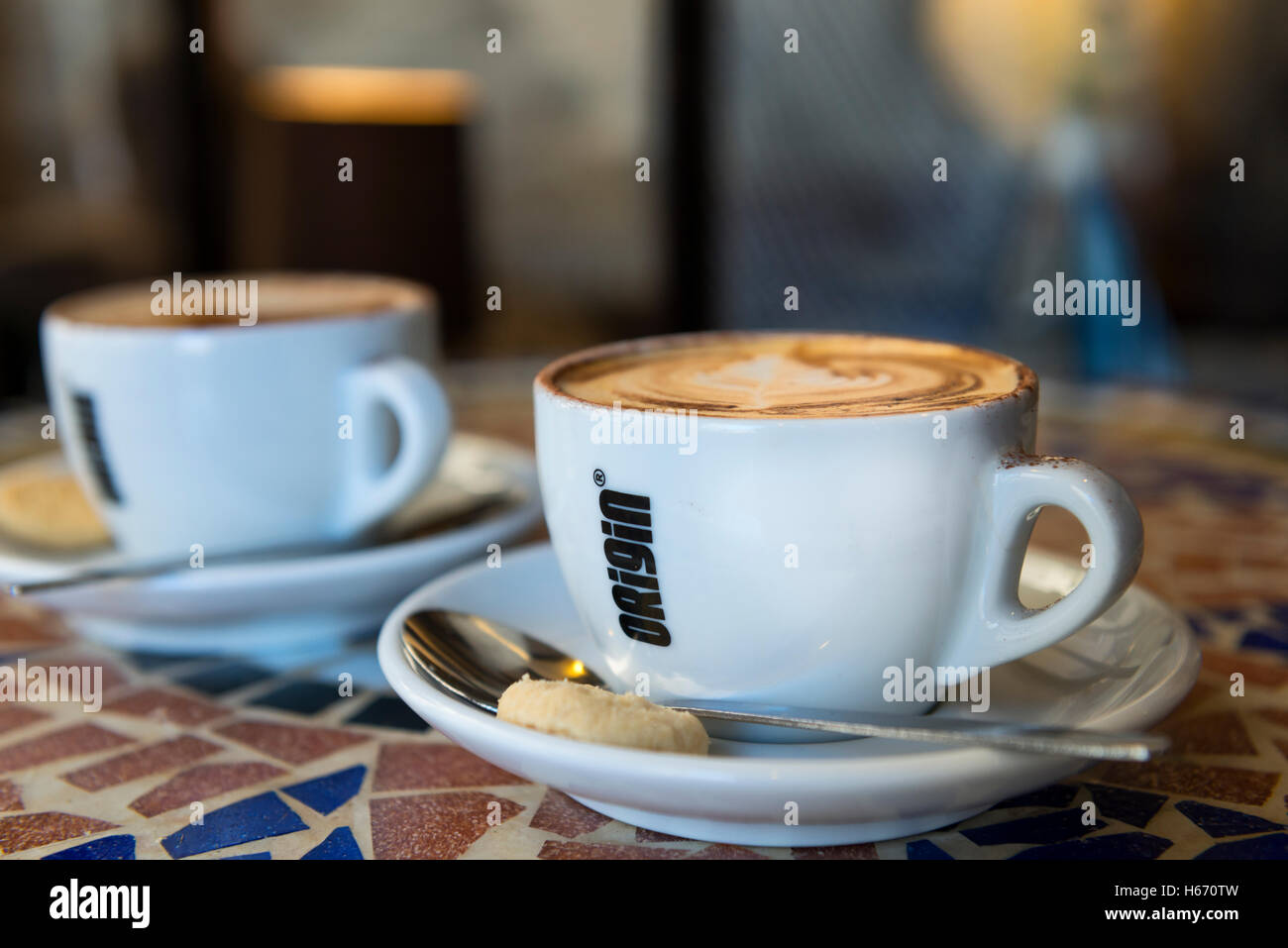 Zwei Cappuccinos auf Mosaik Tisch in Herkunft Kaffeetassen mit Keksen und Löffel Stockfoto