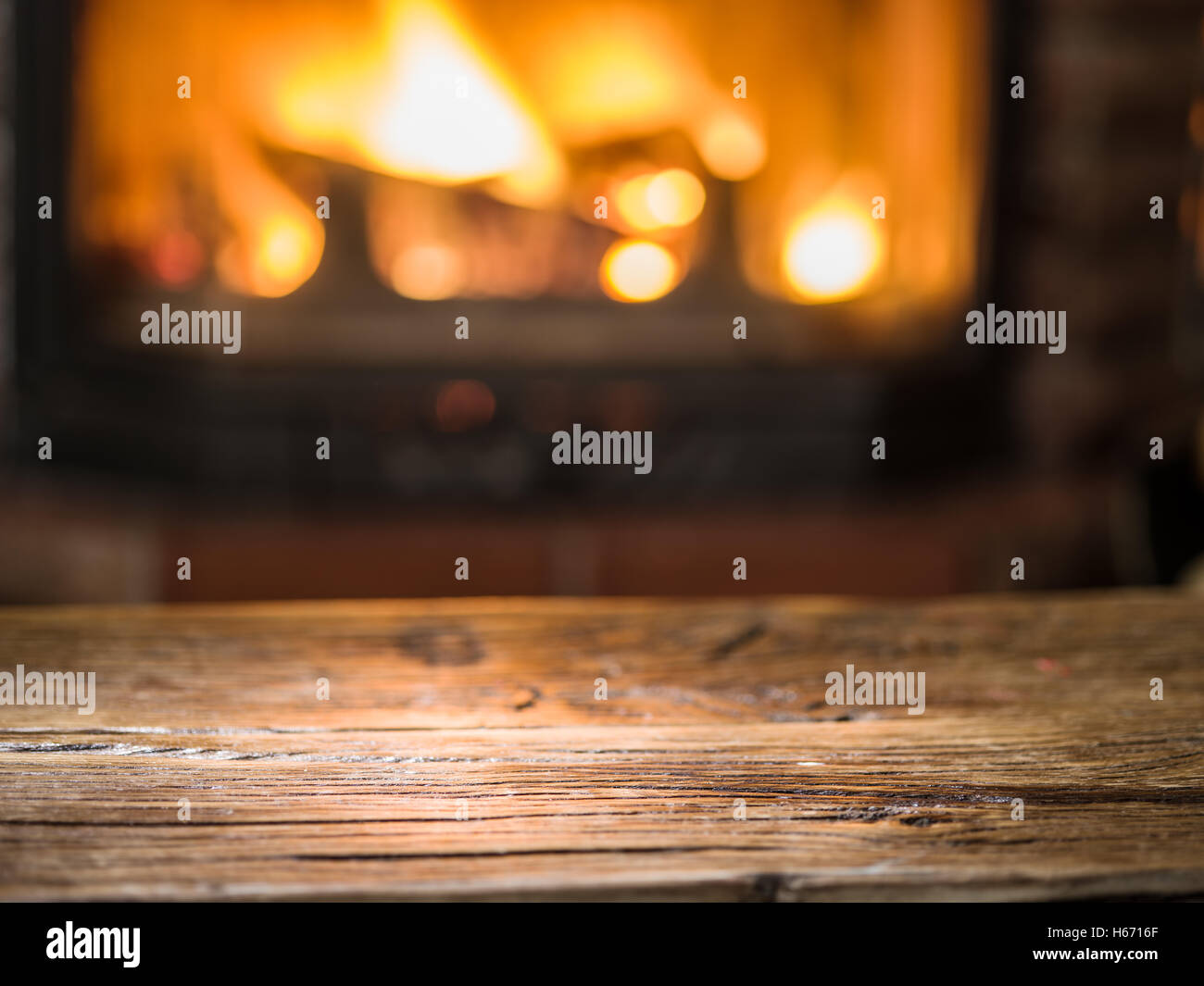 Alten Holztisch und Kamin mit warmen Feuer im Hintergrund. Stockfoto