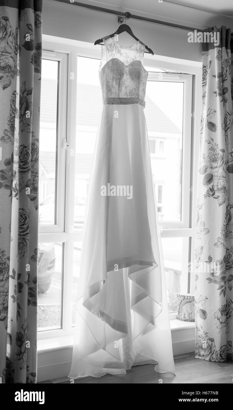 Brautkleid hängen in einem Fenster vertikal in Monochrom, schwarz-weiß genommen. Stockfoto