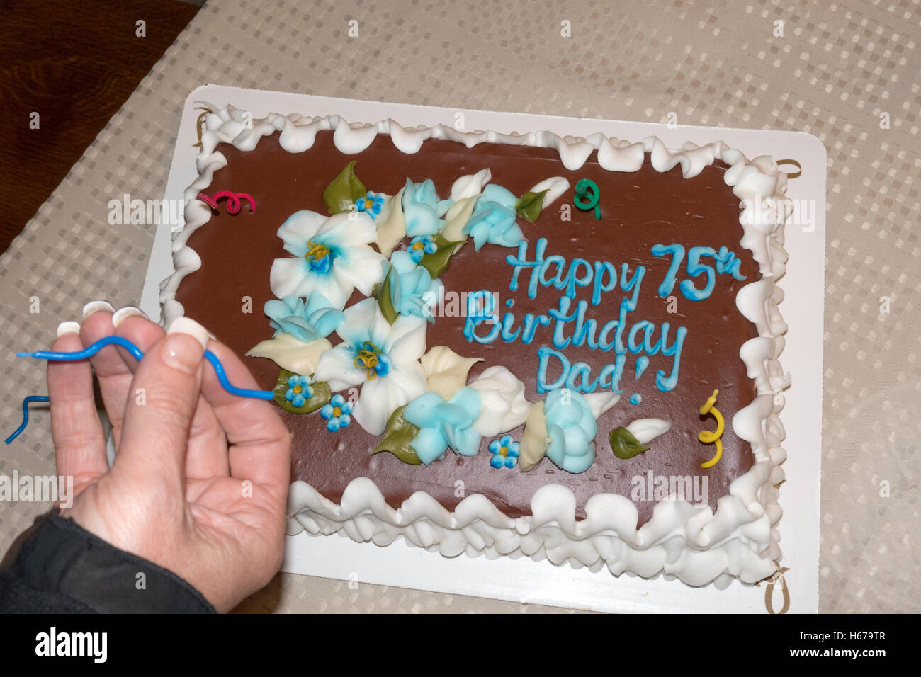 Tochter, platzieren dekorative Spirale Kerzen auf ihre Väter 75. Geburtstagskuchen. Champlin Minnesota MN USA Stockfoto
