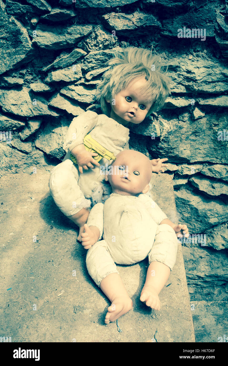 Zwei Puppen, eine Holding Kunststoff Pistole an Kopf andere Puppe im verlassenen Berghaus Stockfoto