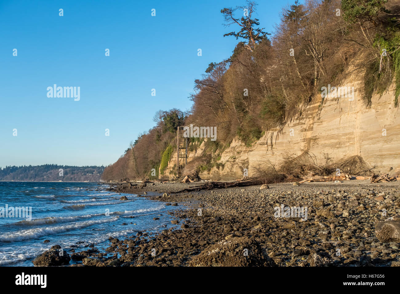 Wellen auf einem felsigen Ufer im Salzwasser State Park im US-Bundesstaat Washington. Eine hohe Struktur ermöglicht Zugang zum Strand. Stockfoto