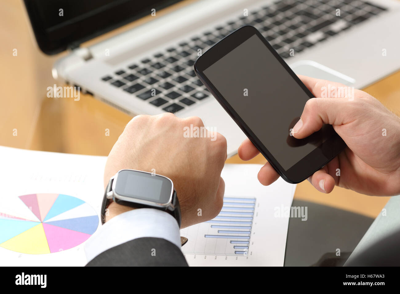 Geschäftsmann Hände Synchronisierung auf Linie eine Smartwatch und Telefon  mit einem Computer im Hintergrund in einem Desktop im Büro sitzen  Stockfotografie - Alamy