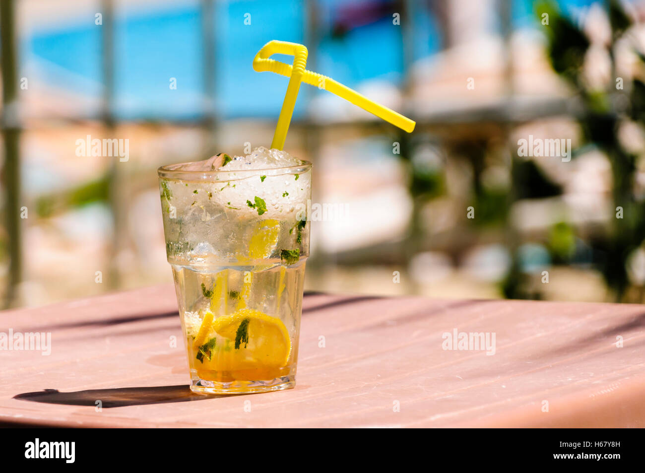 Mojito mit gelben Stroh auf dem Tisch eines Hotels in hellem Sonnenlicht während des Urlaubs Stockfoto