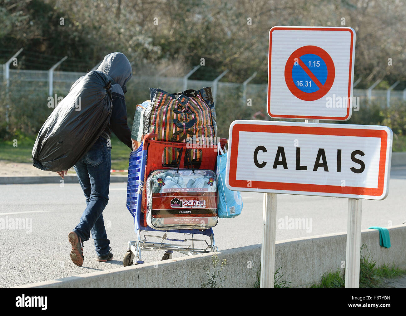 Migranten gehen auf ein Bearbeitungszentrum im "Dschungel" in der Nähe von Calais, Nordfrankreich, da die Massenflucht aus dem Migranten Lager weiter. Stockfoto