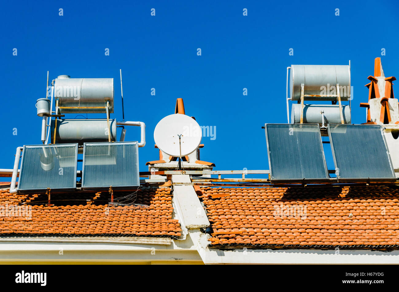 Solare Wasser-heizungen und Satellitenschüsseln auf dem Dach eines Gebäudes in einem heißen Klima Stockfoto