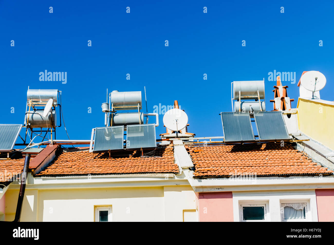 Solare Wasser-Heizungen und Satellitenschüsseln auf dem Dach eines Gebäudes in einem heißen Klima. Stockfoto