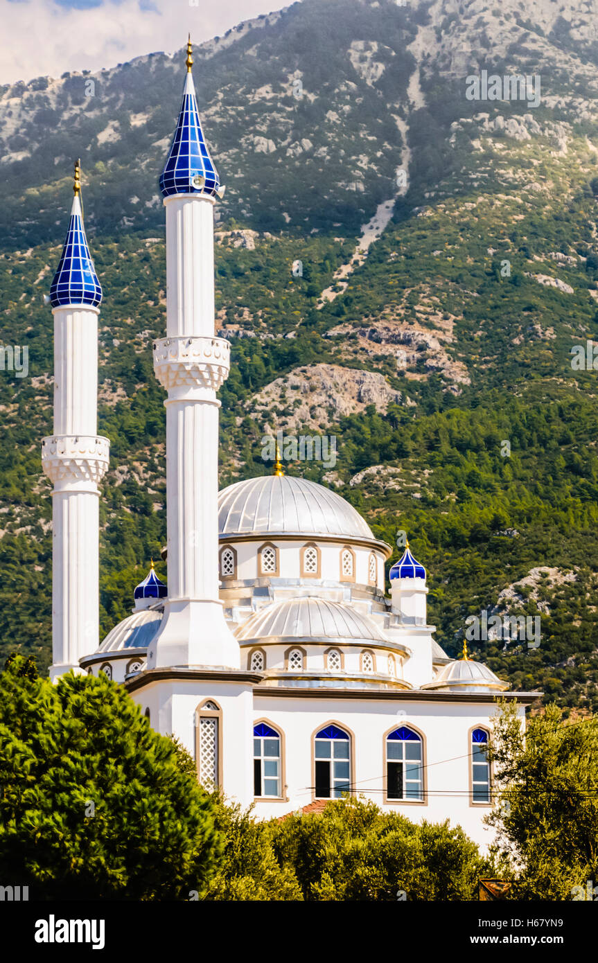 Moschee mit blauem Glas Pinnicles auf der Miranets am Fuße eines hohen Berges mit Wald. Stockfoto