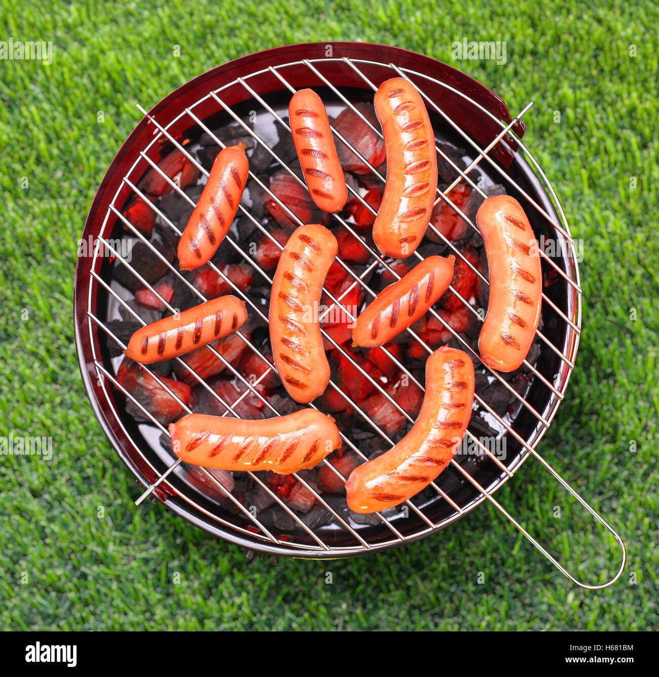 Grillen Würstchen auf dem Grill. Grasgrün Hintergrund. Stockfoto