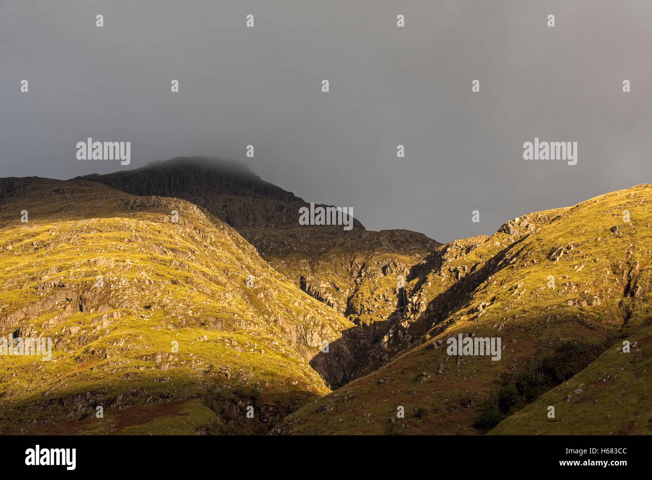 Regenwolke bilden dichten Nebels Abstieg vom steilen Berghang Badeort im Abendlicht, Glen Coe, Schottisches Hochland, Schottland Stockfoto