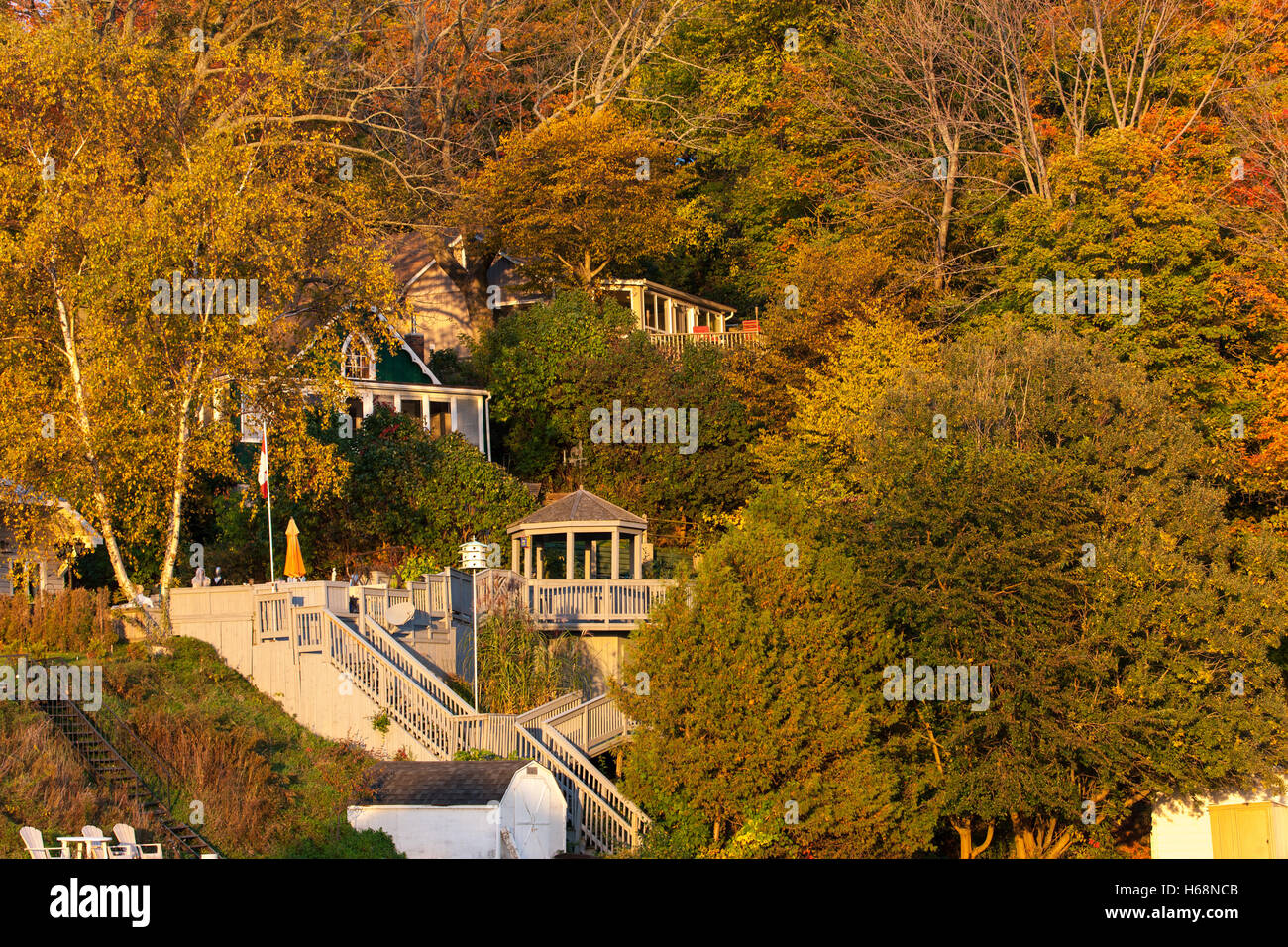 Eine Auflistung der Häuser und Hütten, die abgeschieden von Bäumen, die in der Mitte ihrer Herbst Blüte sind. Stockfoto