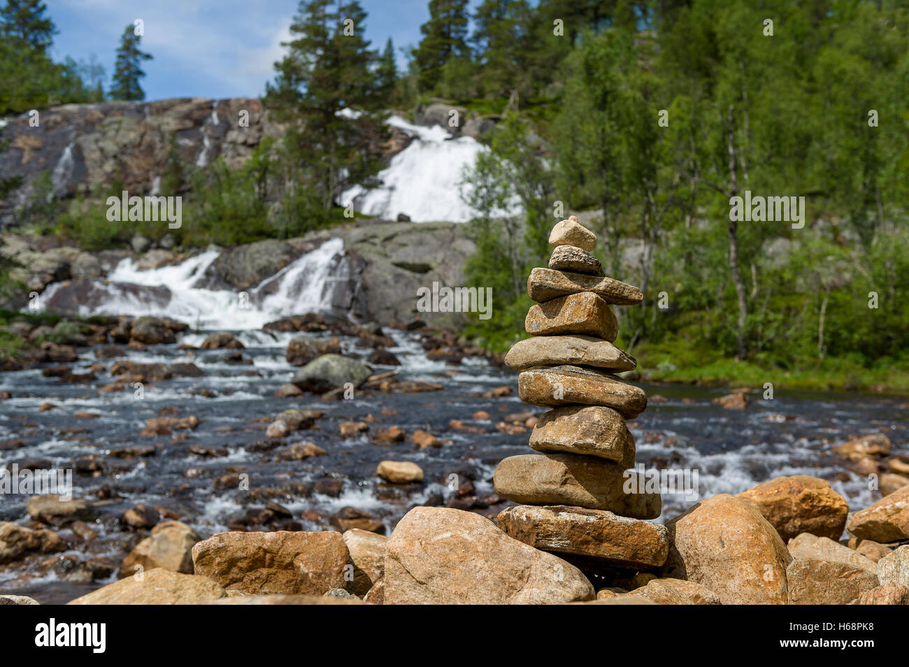 Traditionelle norwegische Steinpyramide auf dem Wasserfall Hintergrund. Stockfoto